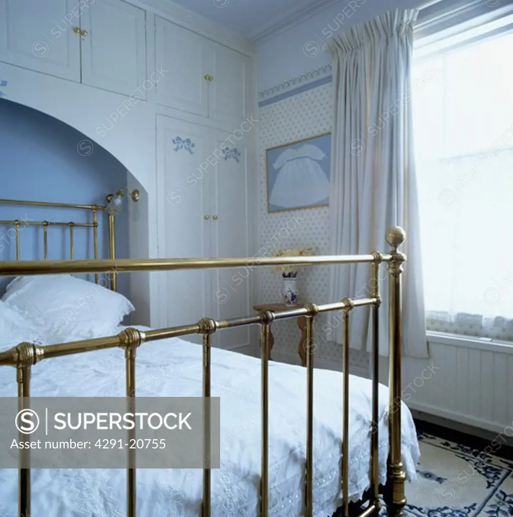 Traditional bedroom with antique brass bed in alcove with built-in storage cupboards