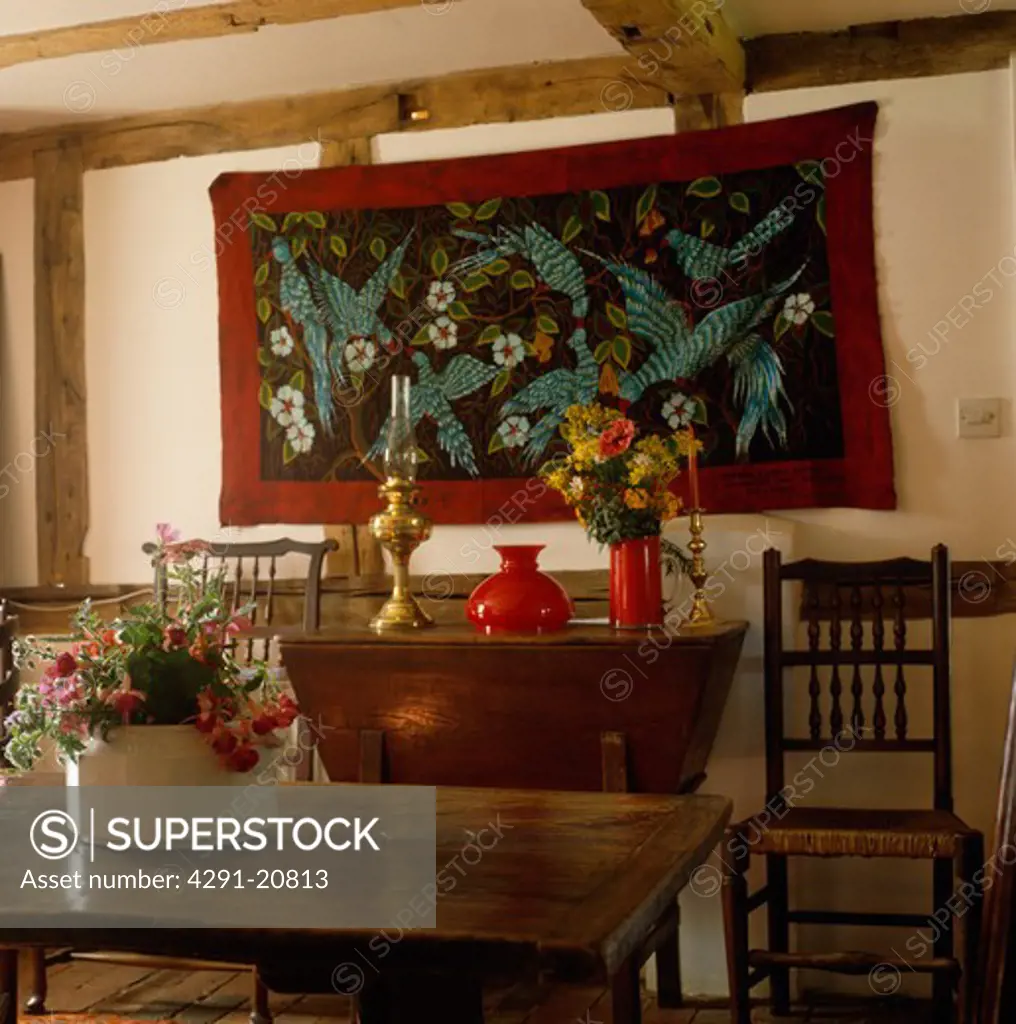 Embroidered collage wall-hanging in country dining room with antique oak table and chairs