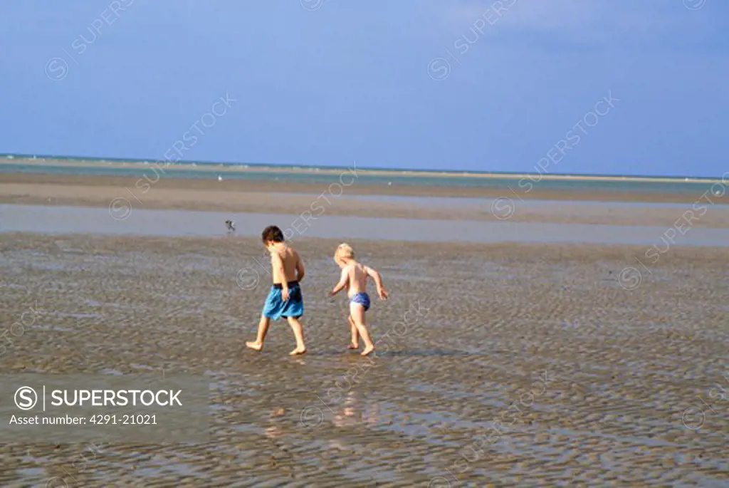 Small boys walking across the sands at Holkham in Norfolk