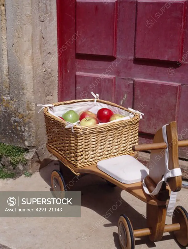 Apples in basket on child's wooden tricycle