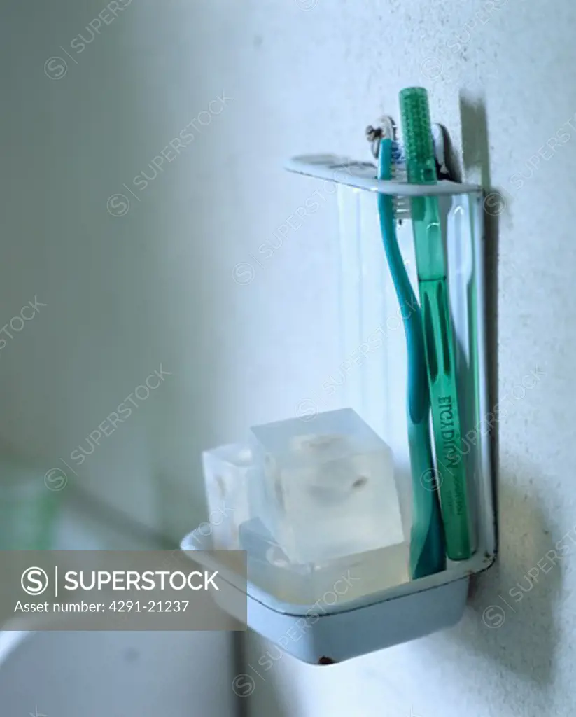 Close-up of toothbrushes and soap in old enamel rack
