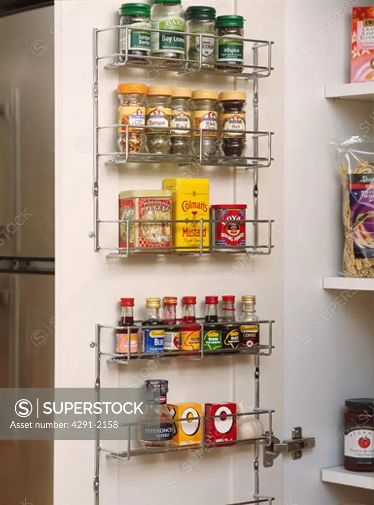 Close-up of spice jars on metal rack on the back of cupboard door