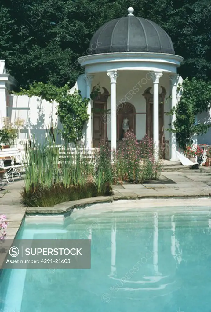 Swimming pool and classical gazebo in large country garden