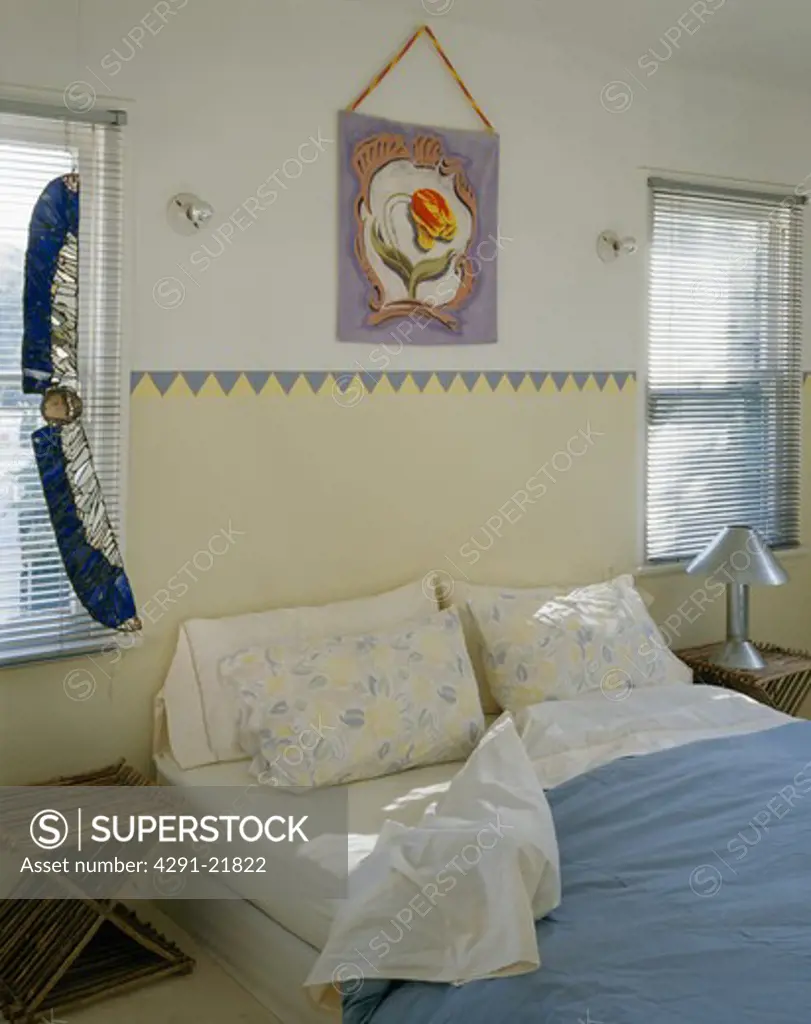 Stained glass ornament on window in bedroom with painted border above bed