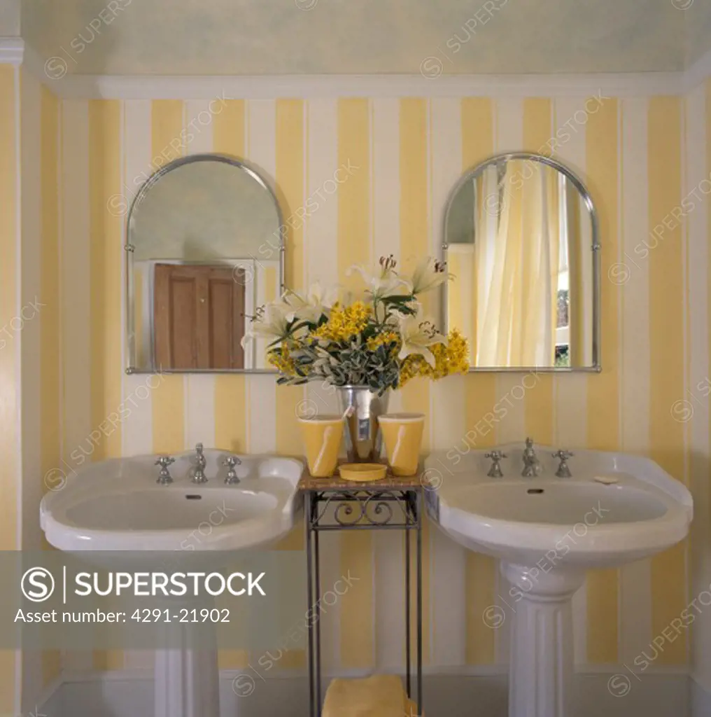 Arched basins above white double pedestal basins in bathroom with yellow striped wallpaper
