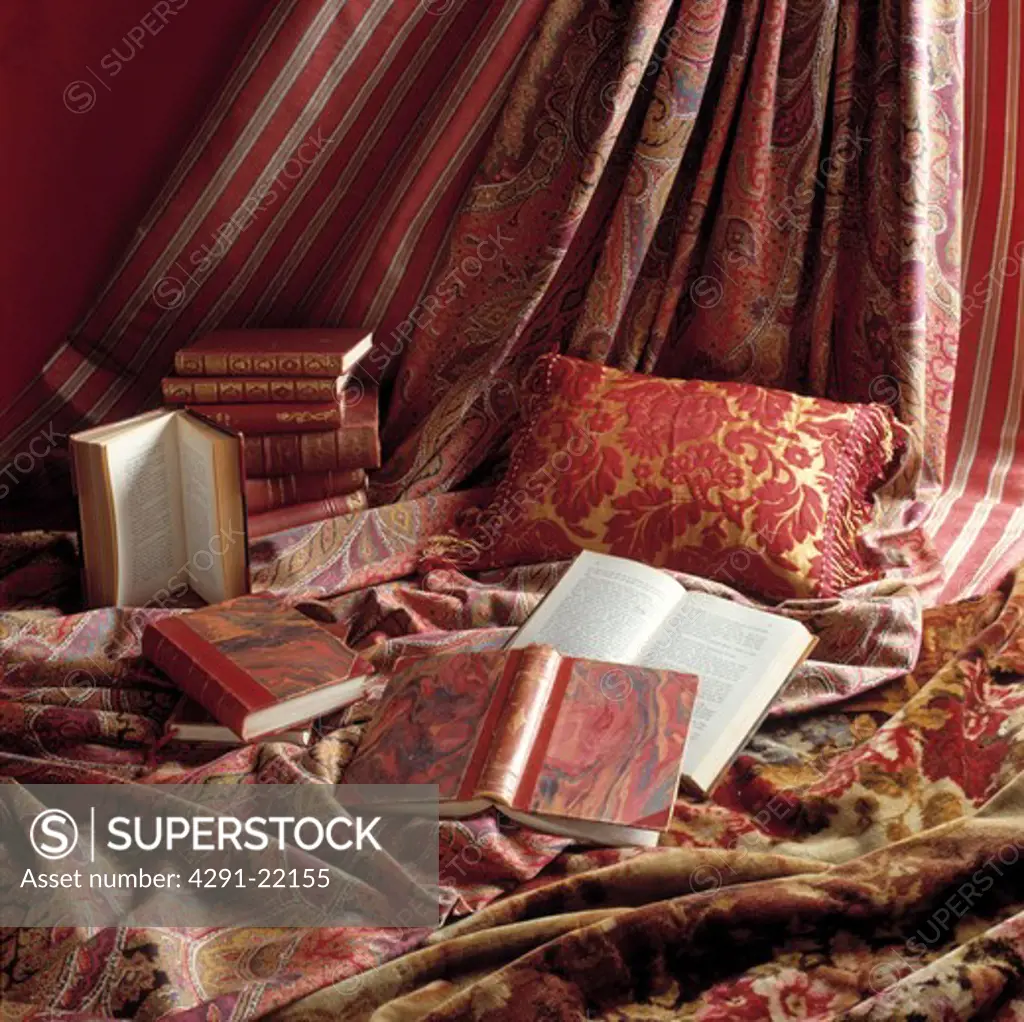 Close-up of books and red patterned cushion and curtains