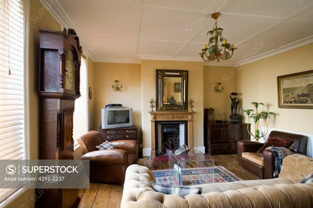Thirties leather club chairs and perspex table in living room with antique mirror above fireplace