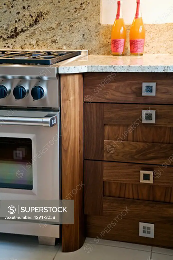 Close-up of steel oven and walnut kitchen unit with granite worktop