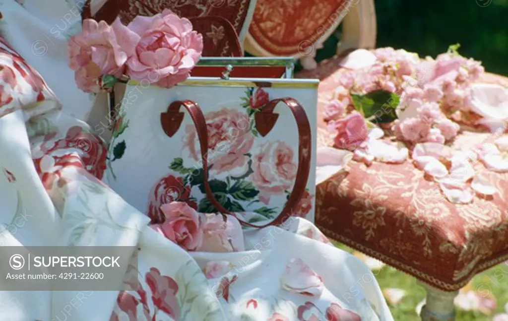 Still-life of pink roses in rose-patterned handbag on floral fabric