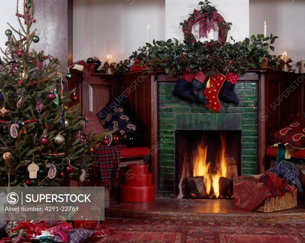 Foliage garland above fireplace with lighted fire in hall with decorated Christmas tree