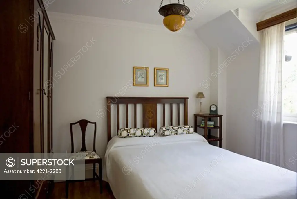 White linen on bed in small white uncluttered bedroom
