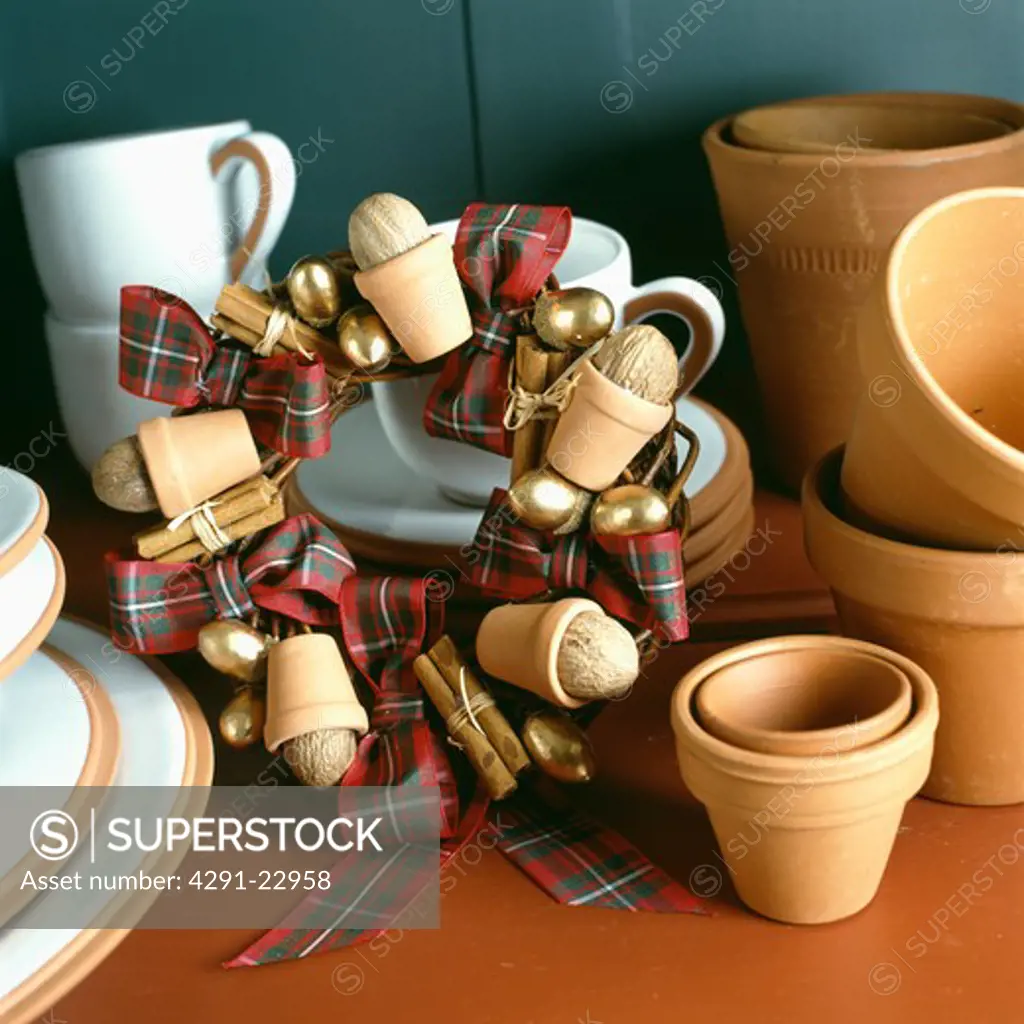 Close-up of terracotta pots beside home-made Christmas wreath of miniature terracotta pots with tartan ribbon