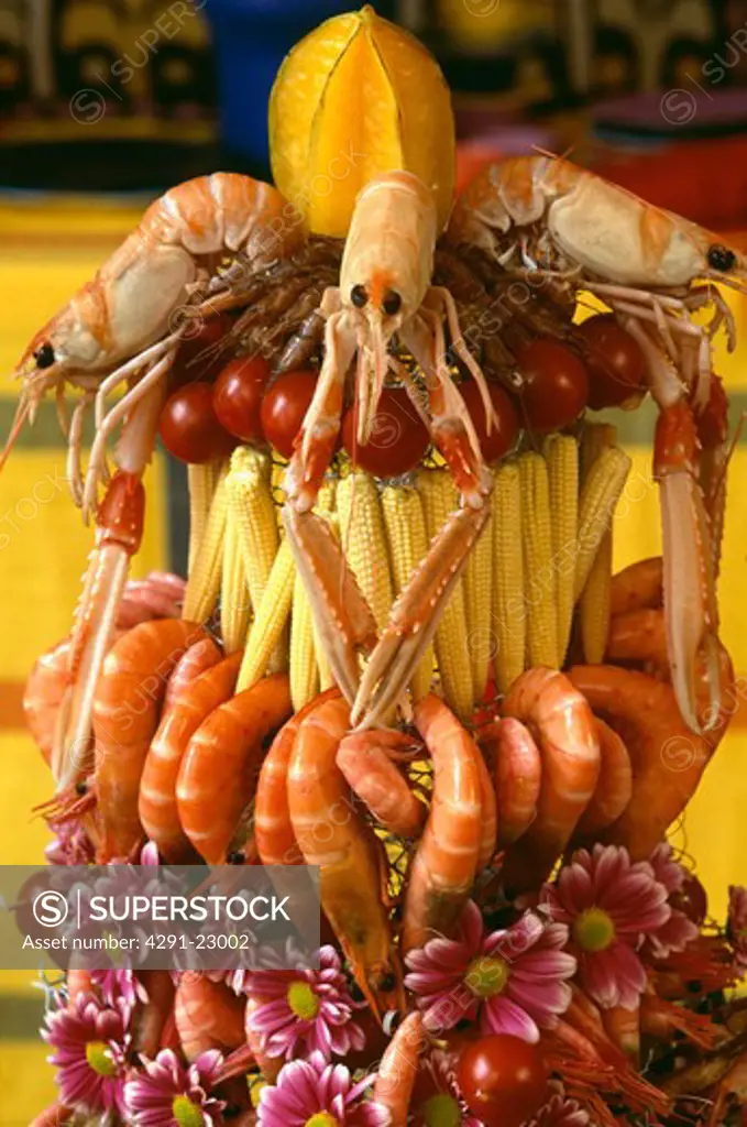 Close-up of table decoration of shellfish with small corn-on-the-cob and pink daisies