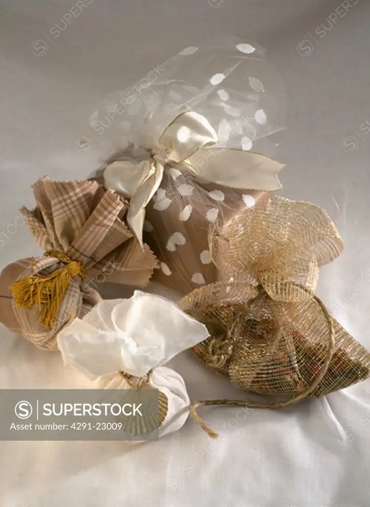 Close-up of gold and white gift bags tied with gold string and decorated with gld tassels and seashells