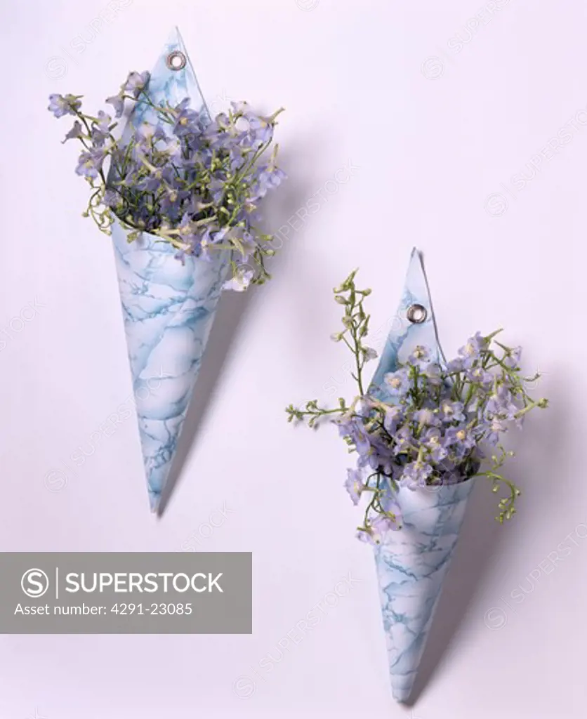 Close-up of blue summer flowers in hand-made ceramic cone-shaped wall vases