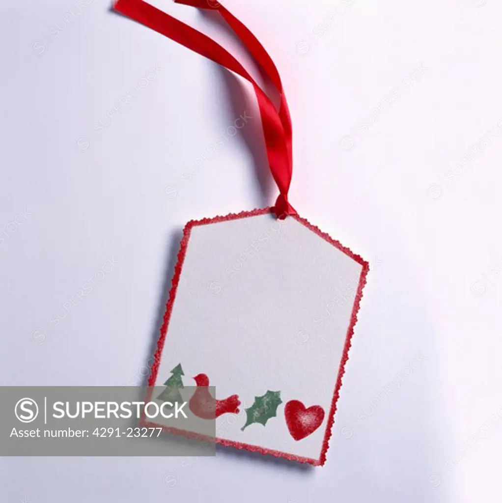 Close-up of home-made white paper gift-tag with painted motifs