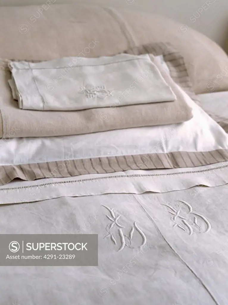 Close-up of natural linen pillowcases and pillow on bed with monogrammed linen bedcover
