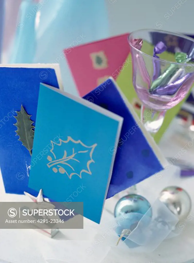 Close-up of silver card holder with blue Christmas cards with gold stencilled holly leaf pattern