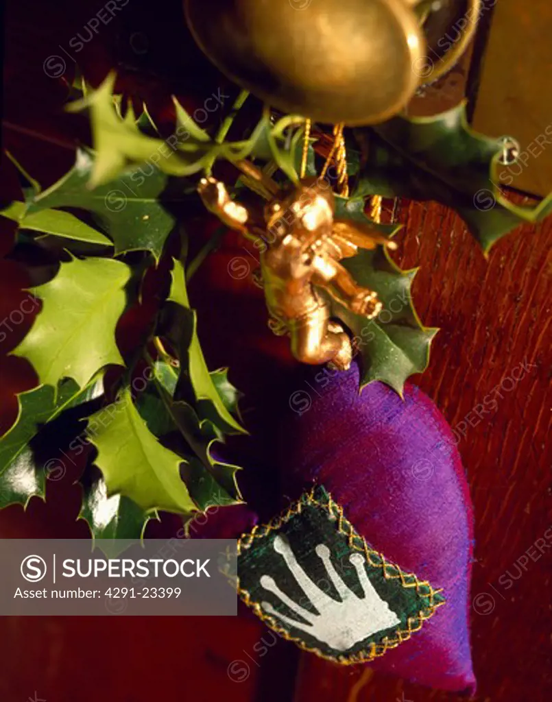 Close-up of holly with small gold cherub and appliqued purple silk sachet