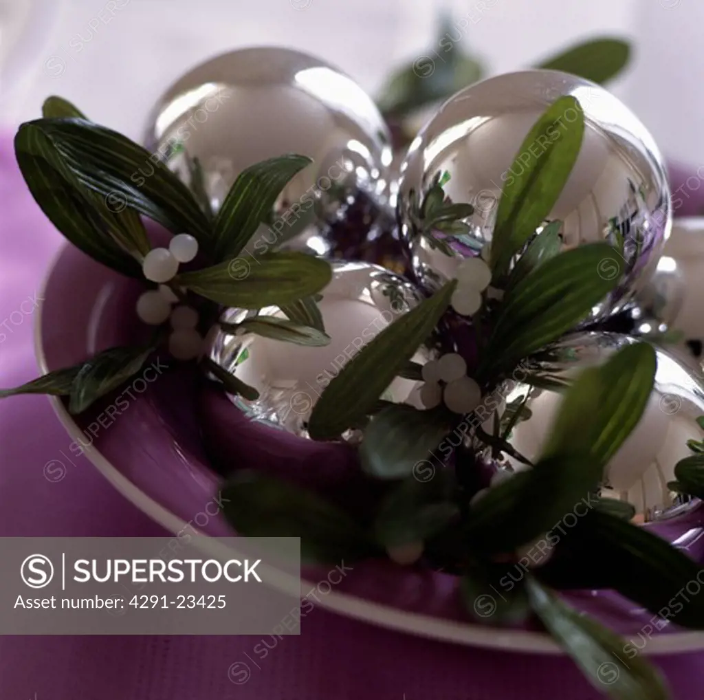 Close-up of silver glass baubles with sprig of mistletoe