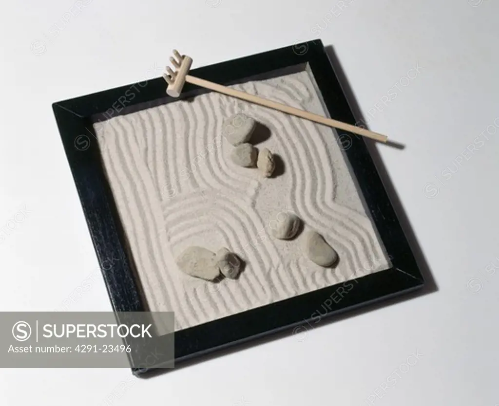 Sand and pebbles in miniature Zen garden with rake