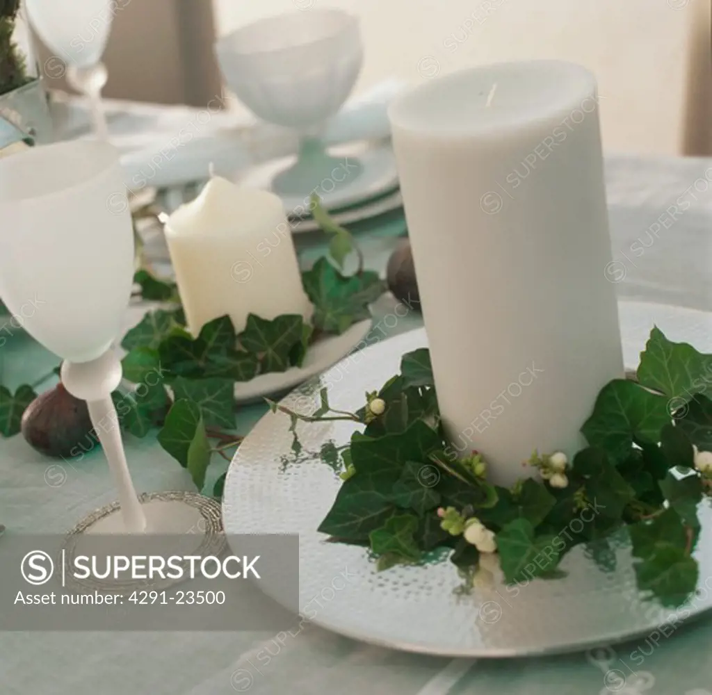 White frosted glass and white candle on white plate decoration with ivy leaf garland on dining table
