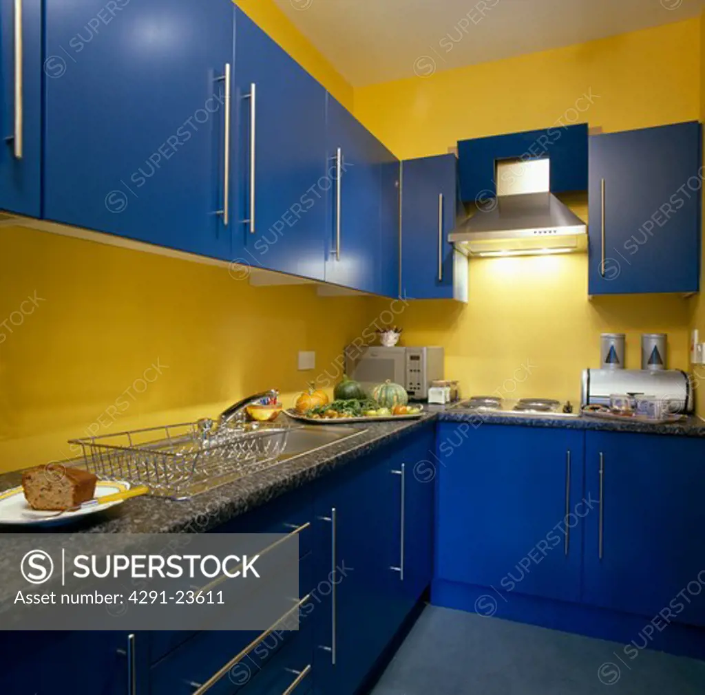 Yellow kitchen with bright blue fitted cupboards and granite worktops