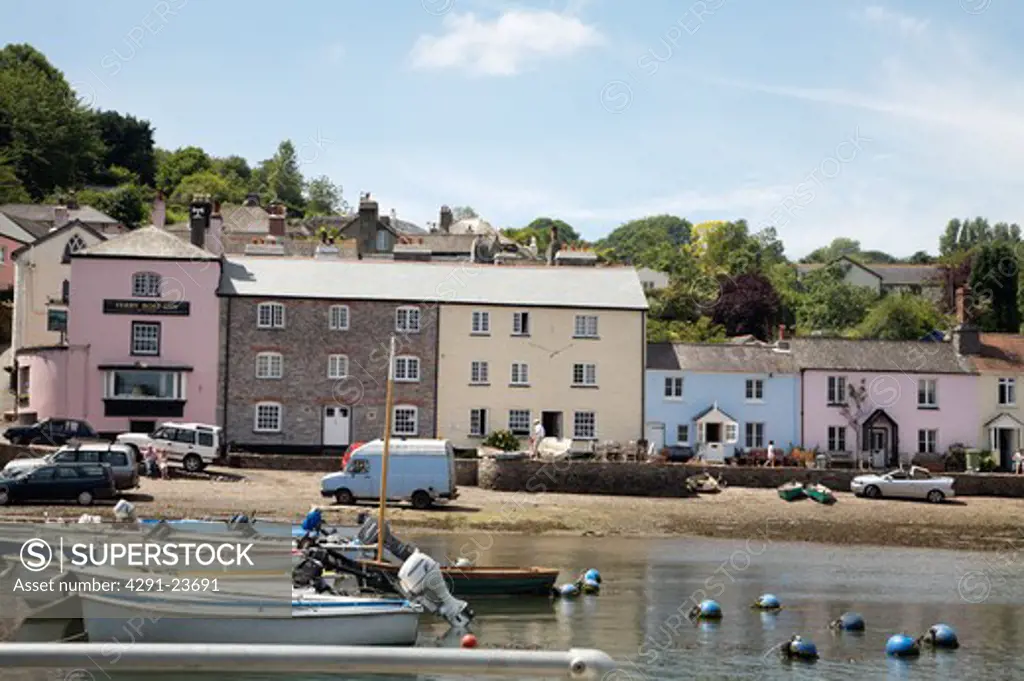 Boats pulled up in small harbour with pink and blue painted h houses in small coastal town