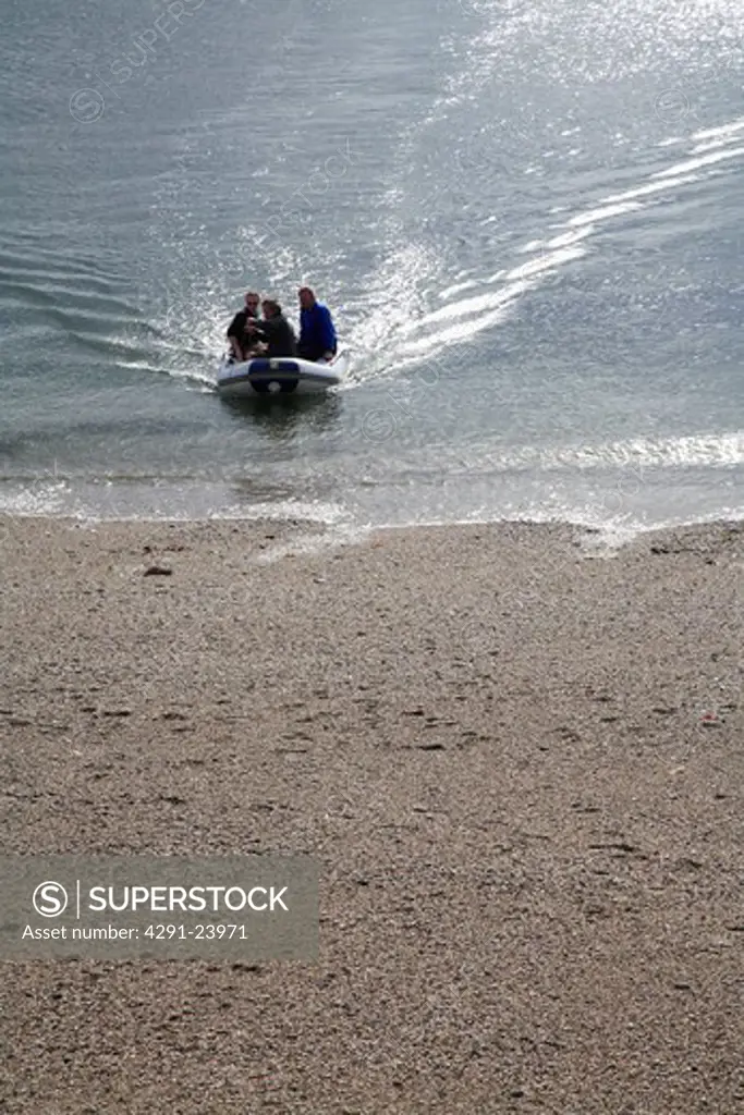 People in boat coming into land on Cornish beach
