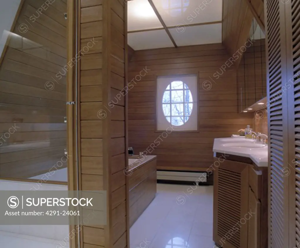 Modern wood panelled bathroom with opaque glass ceiling panels and white tiled floor