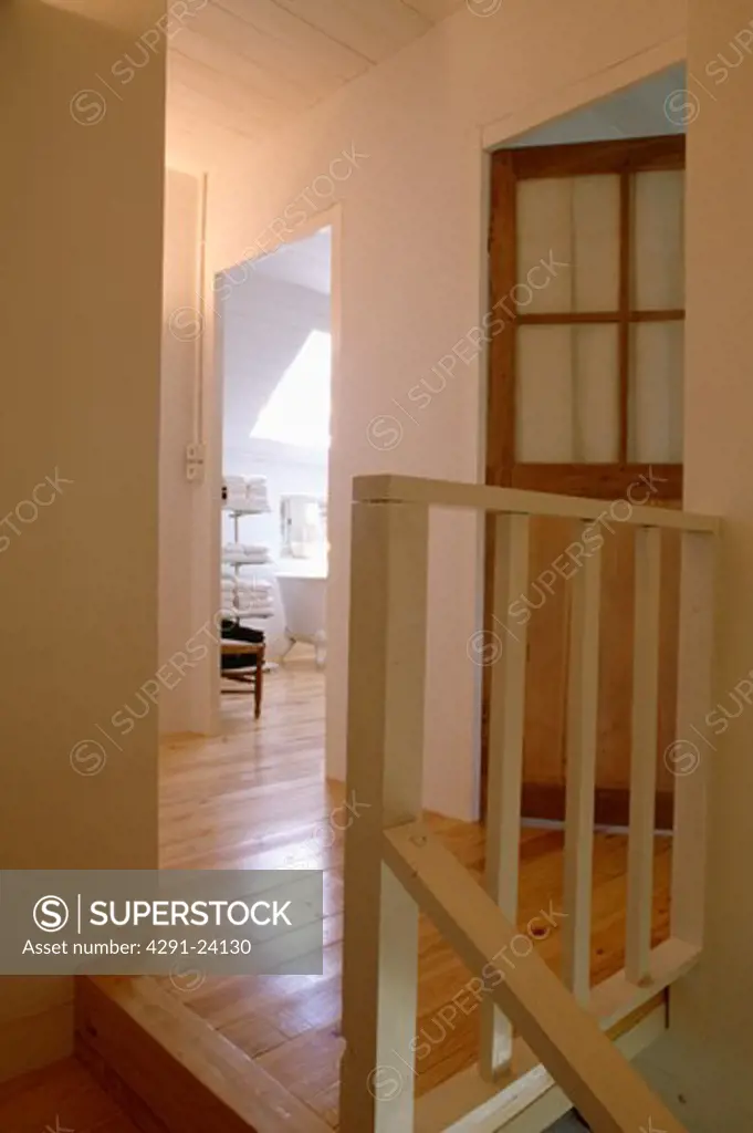 Wooden flooring on small white landing with wooden bannisters