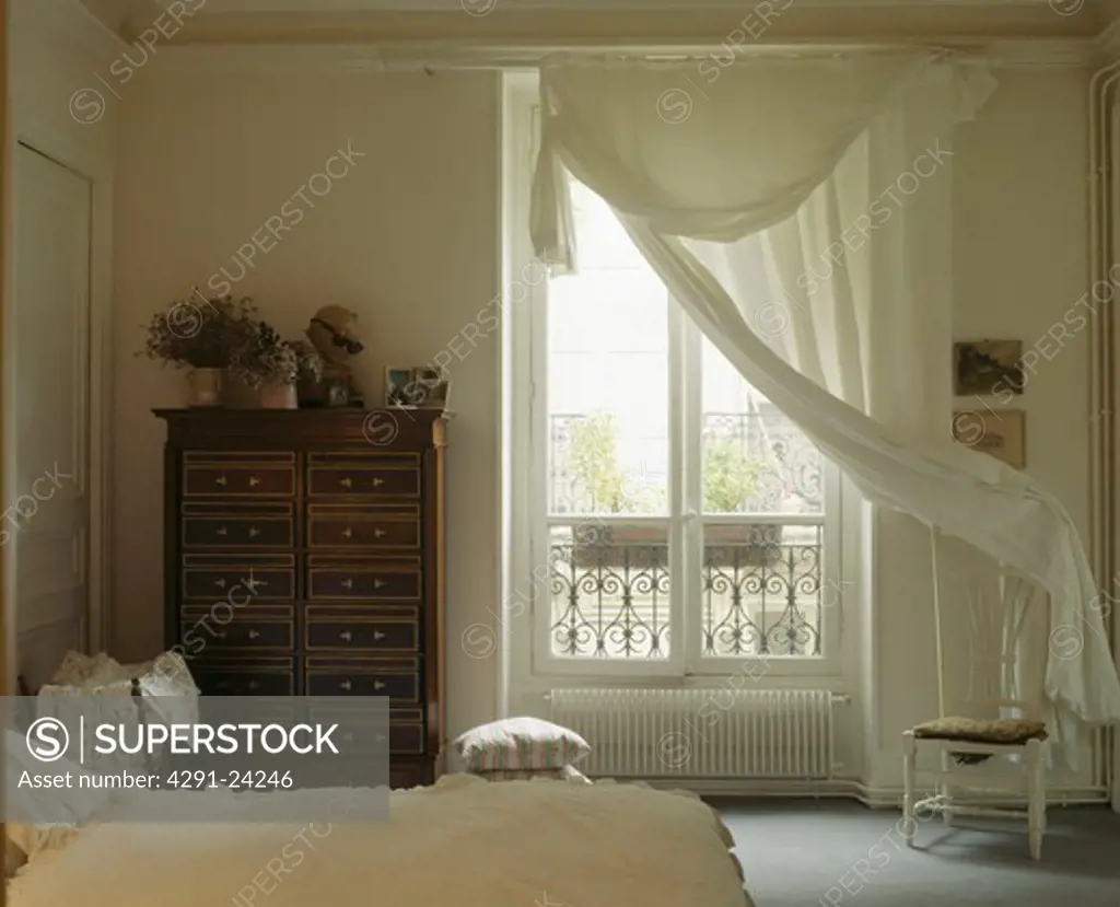 Cream voile curtains at French windows in white traditional townhouse bedroom