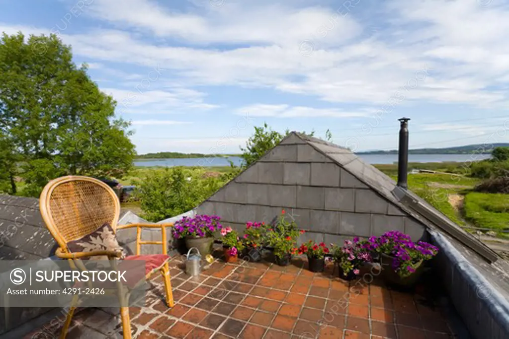 Wicker chair on roof garden of cottage with view of lake