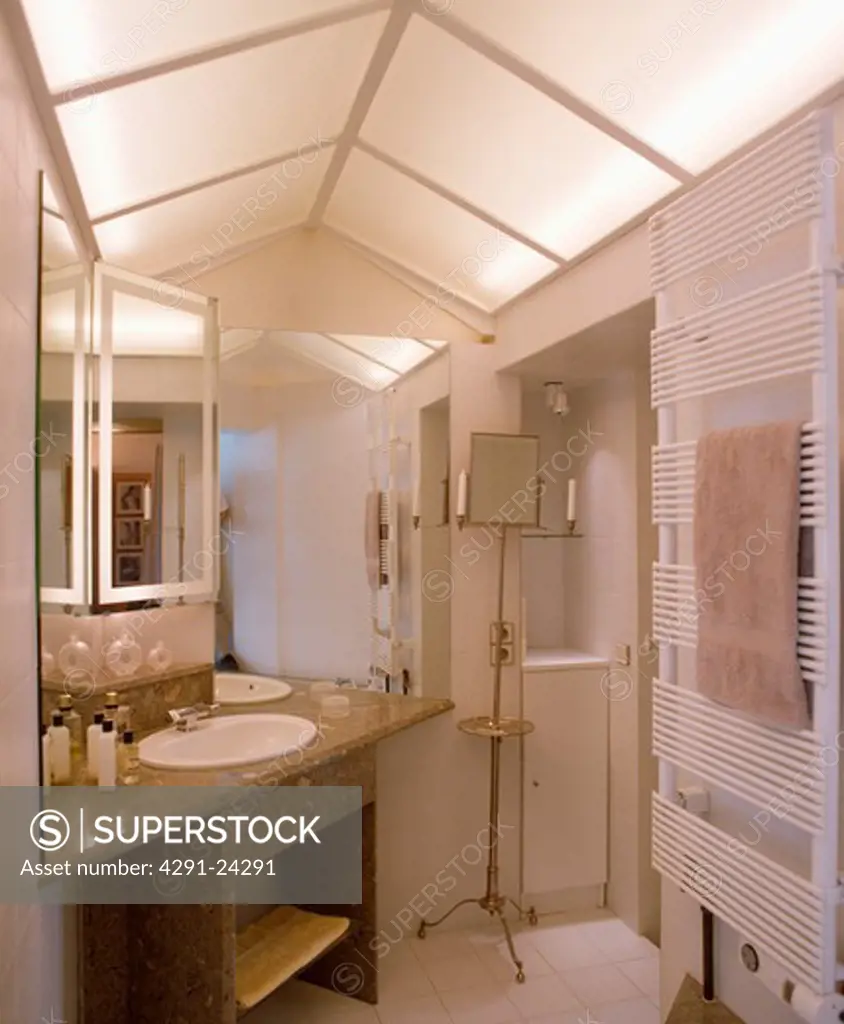 Lighted opaque glass panels on apex ceiling modern white bathroom with basin set into marble vanity unit