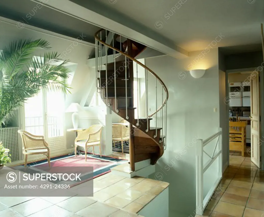 Spiral staircase and wicker chairs on tiled floor in openplan landing