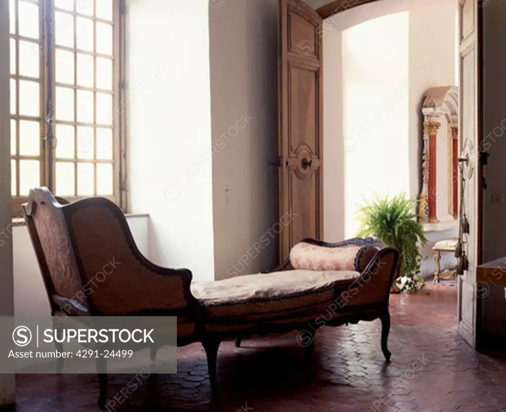 Upholstered antique chaiselongue in traditional living room