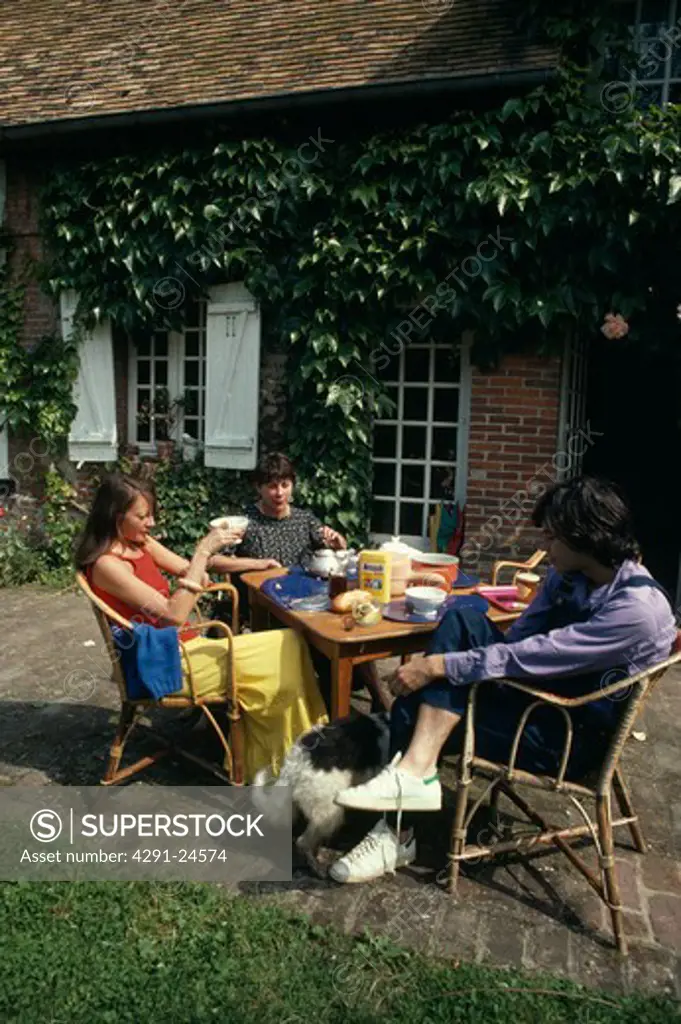 Children having tea at table outside French country house