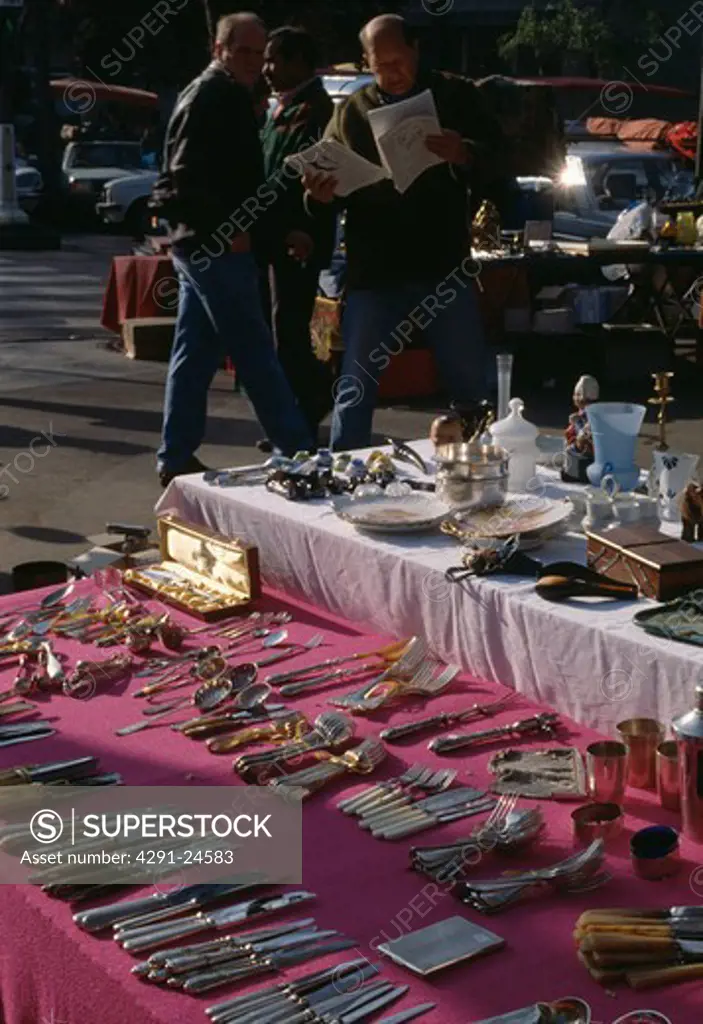 Stall-holder and customers browsing at cutlery stall at street market in Paris