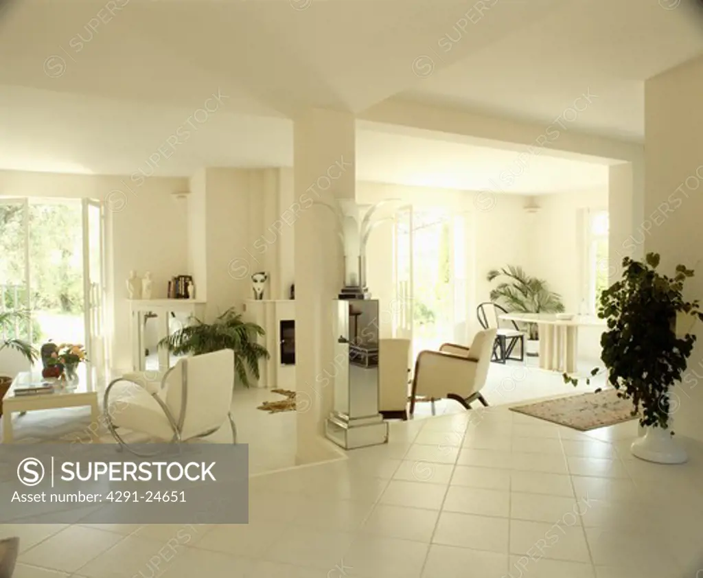 Split-level open-plan modern white living room with white tiled floor and white armchairs