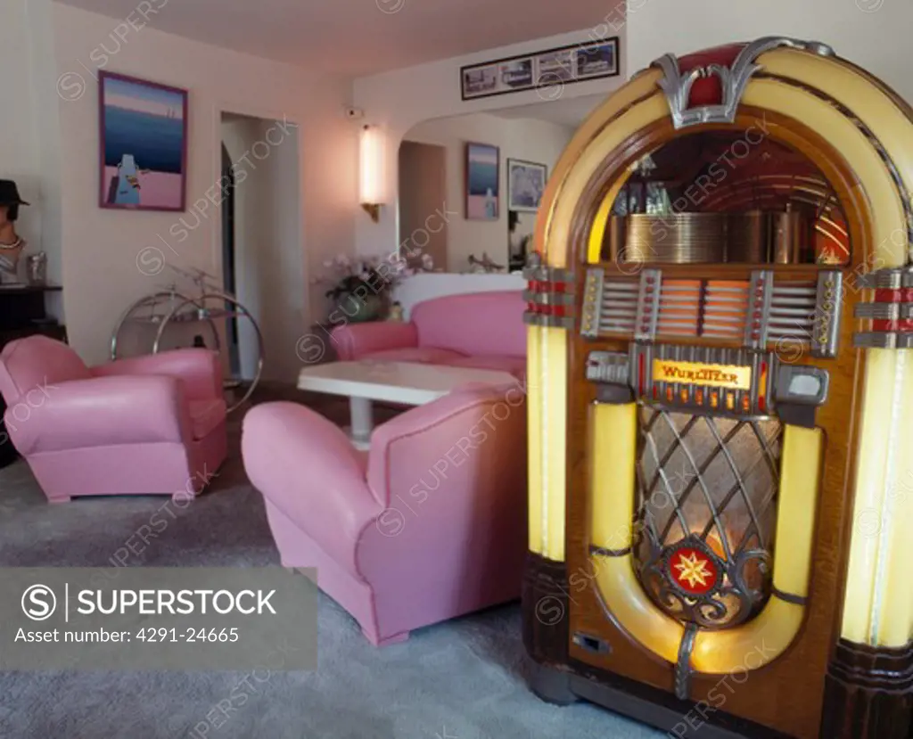 Wurlitzer jukebox in living room with pink leather armchairs