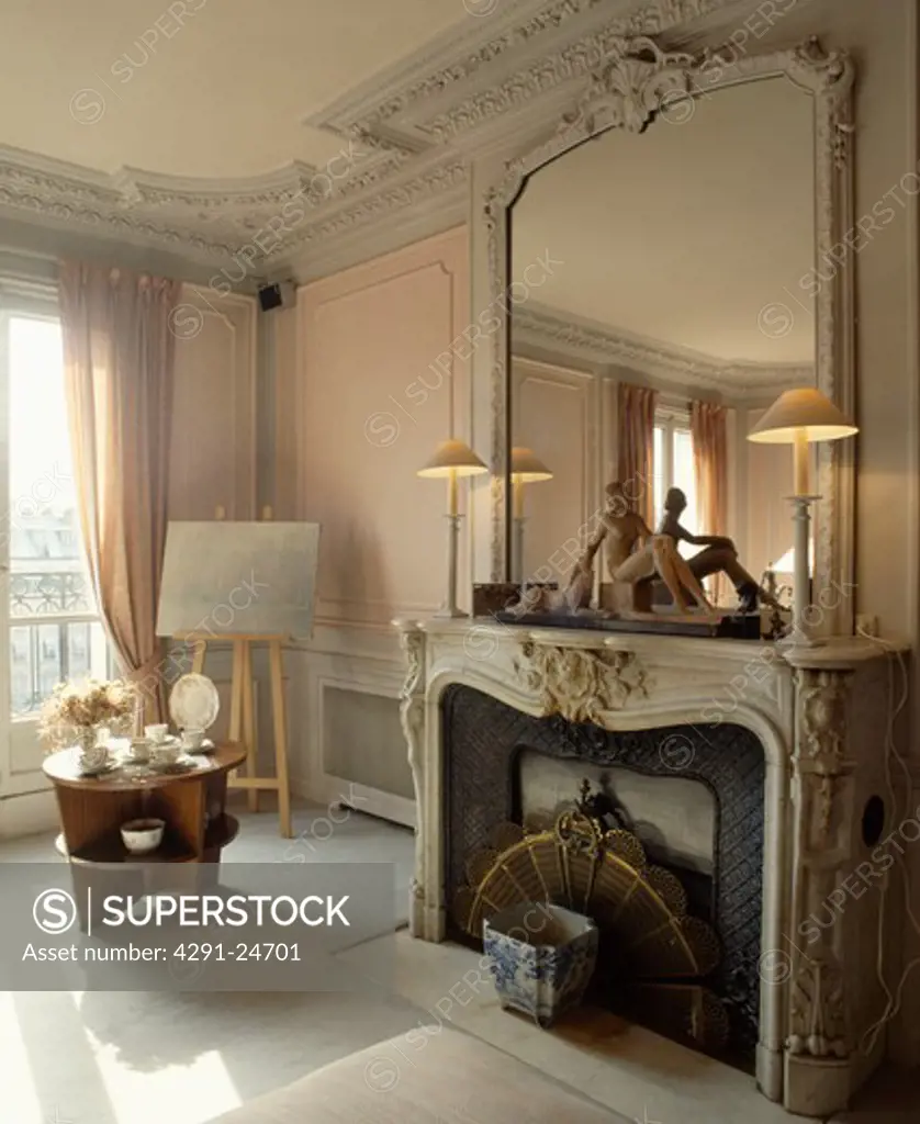 Ornate mirror above marble fireplace in traditional French living room
