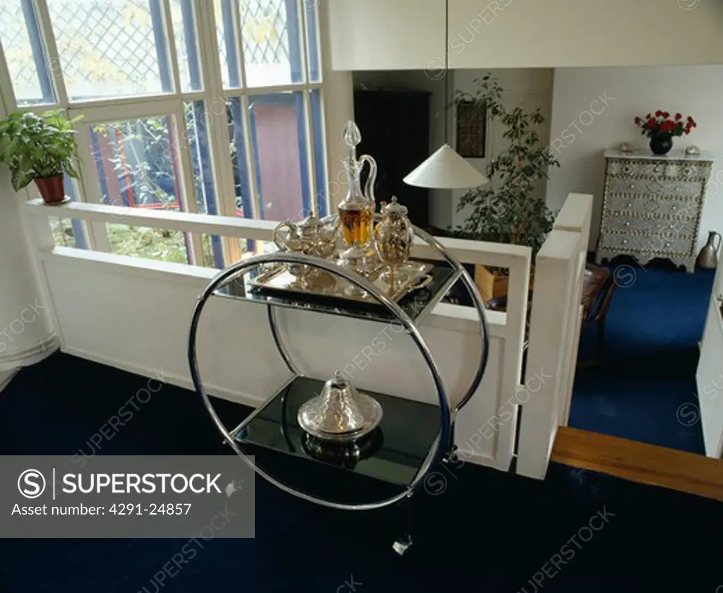 Glass decanter and silver teapot on Art Deco chrome and glass table on landing