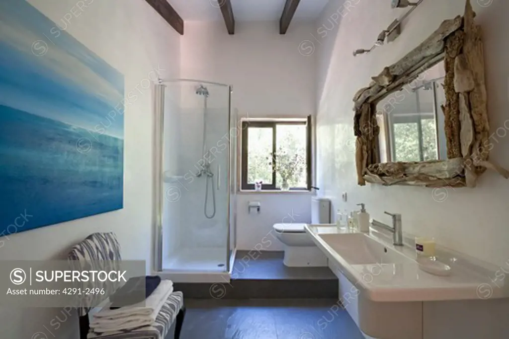 Large painting and driftwood mirror in white Mediterranean bathroom with blue flooring