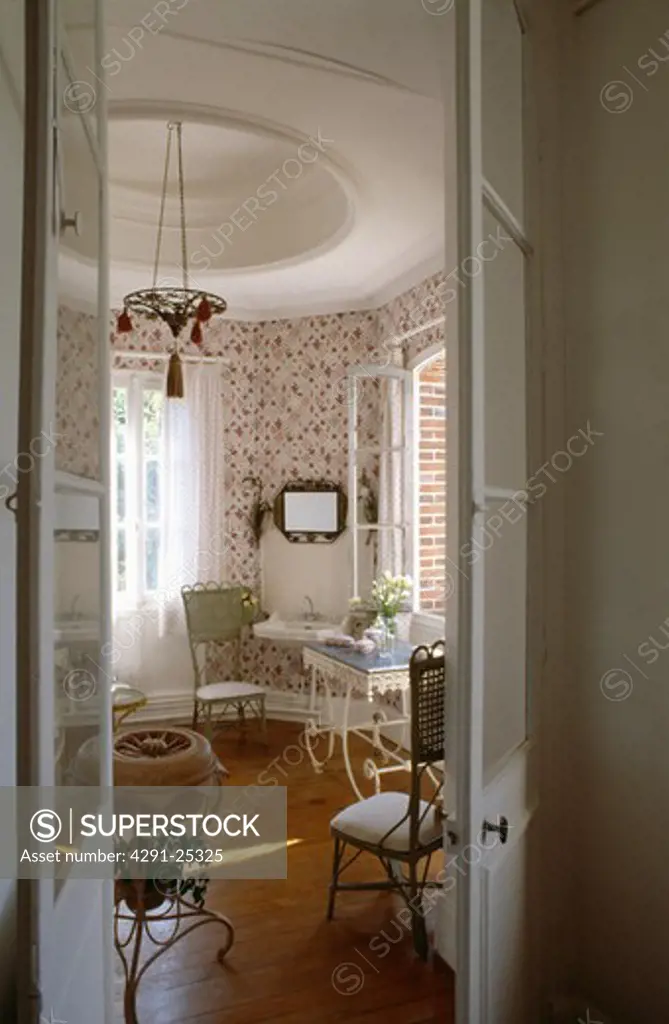 Open double doors to traditional white dining room with circular ceiling detail and wooden flooring
