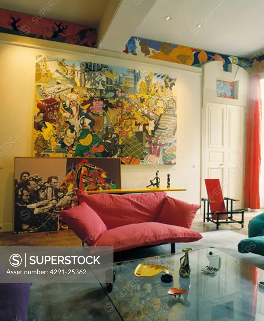 Large abstract painting above red sofa in modern living room and glass coffee-table
