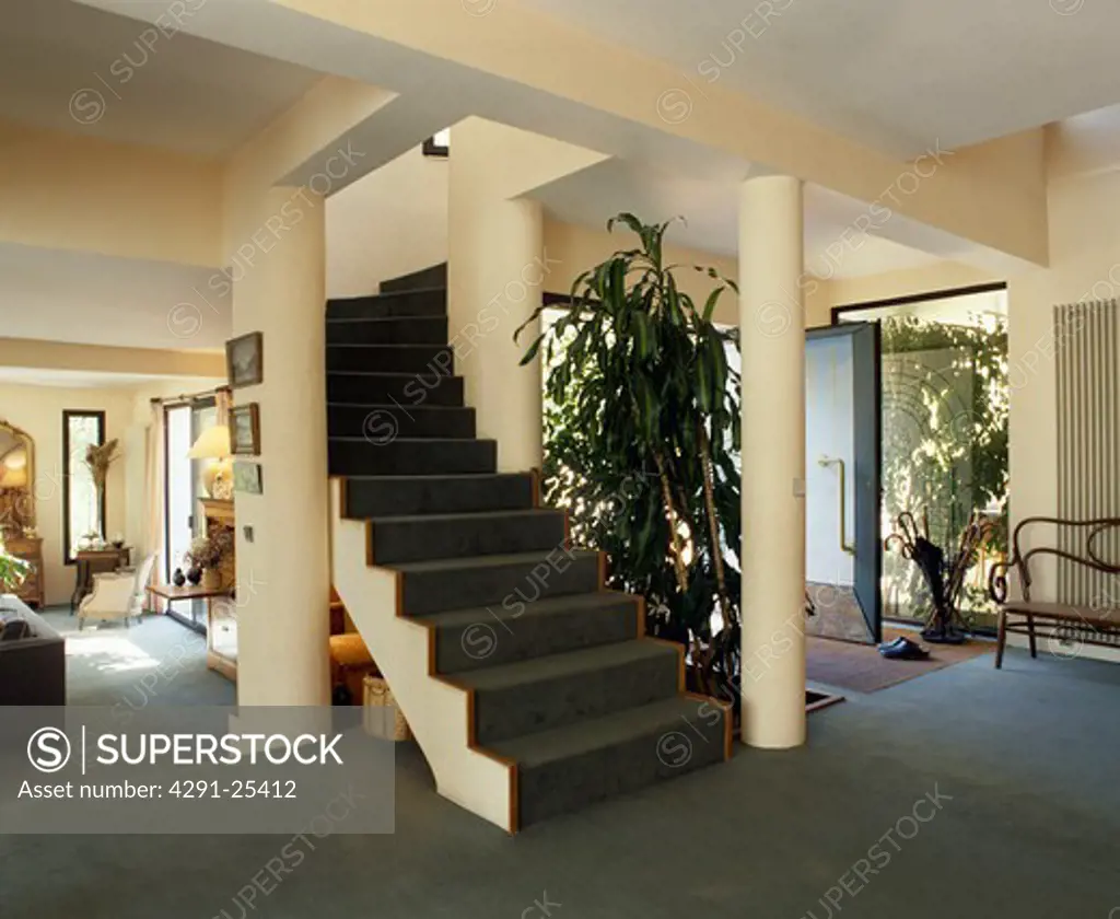 Pillars on either side of open staircase in large openplan hall with grey carpet
