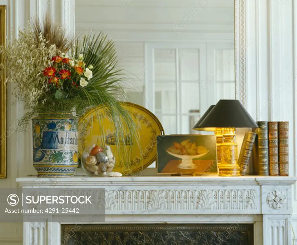 Close-up of flowers in vase on mantelpiece with lamp and old books