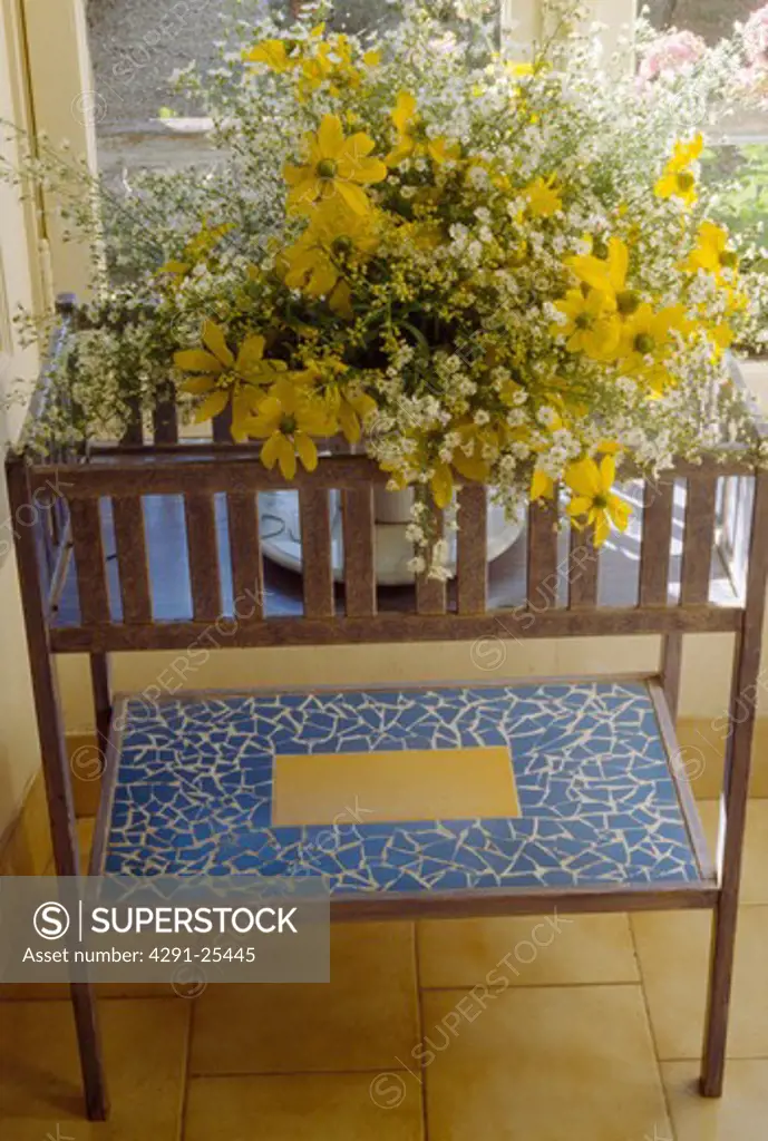 Close-up of branches of yellow blossom in vase on blue enamelled table