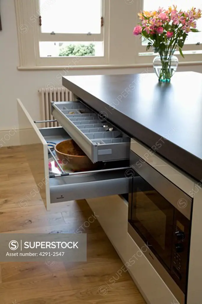 Modern kitchen with open storage drawers on island unit with cast concrete resin worktop