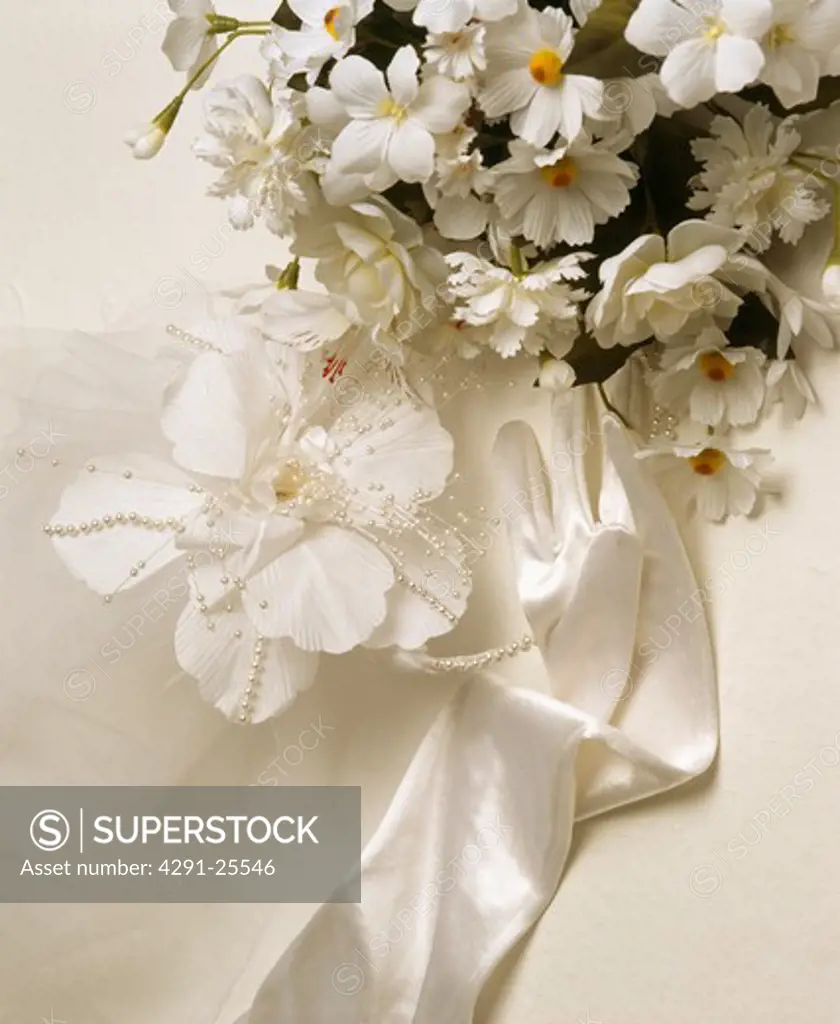 Close-up of white faux flower wedding decoration with single white satin glove